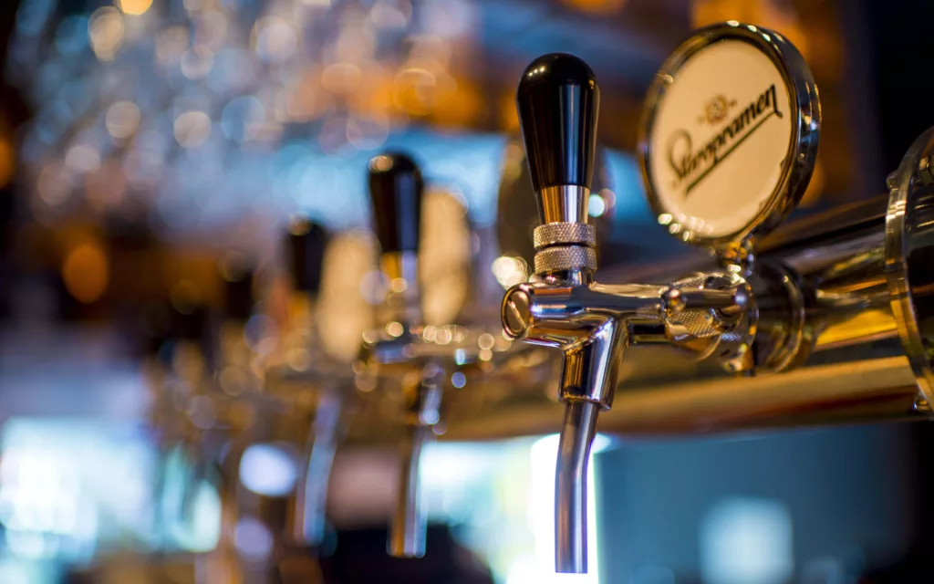 Beer taps in a row with sparkly lights in the background.