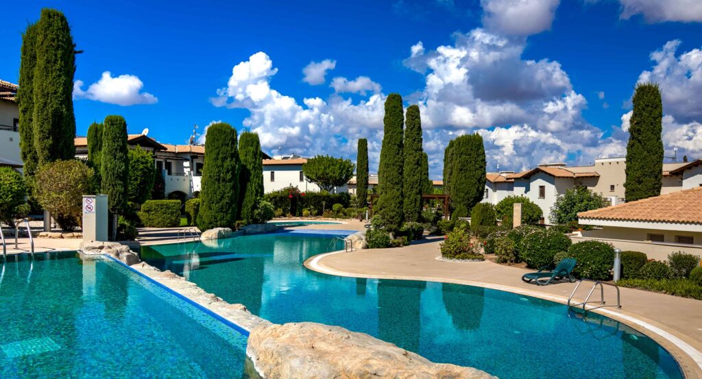 View of Helios Heights communal pool on Aphrodite Hills. Looking from the top pool, over the lower pool, showing large poolside terrace with pretty gardens.