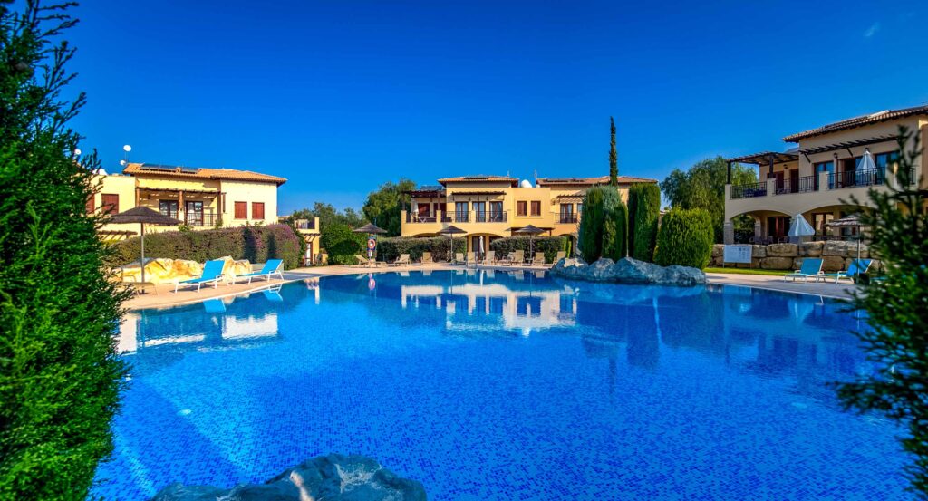 View of Theseus Village communal pool, looking over the water to apartment blocks. Aphrodite Hills Resort Cyprus.