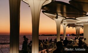 Antasia Beach Club in Paphos, shadows of people with drinks in the foreground with deep red sunset in the background.