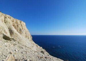 White Cliff against a clear horizon blue sea line and blue sky. Cape Aspro, Pissouri, Cyprus.